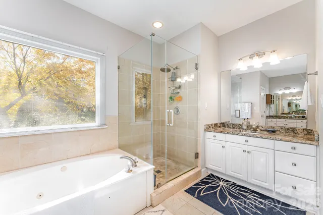 a bathroom with a granite countertop sink a large mirror a bathtub and next to a window