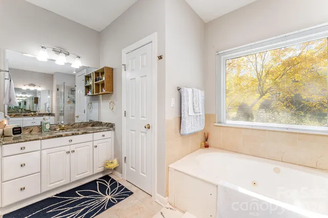 a spacious bathroom with a granite countertop sink mirror and a bathtub