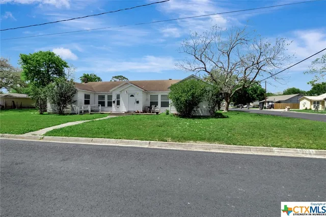 a view of a house with a yard and large trees