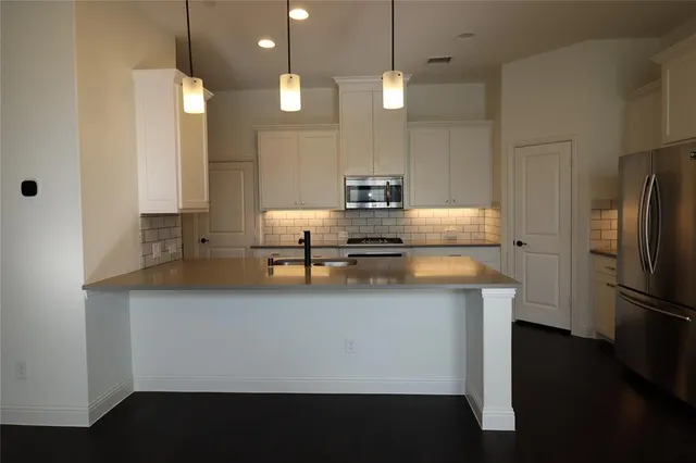 a kitchen with kitchen island white cabinets and stainless steel appliances
