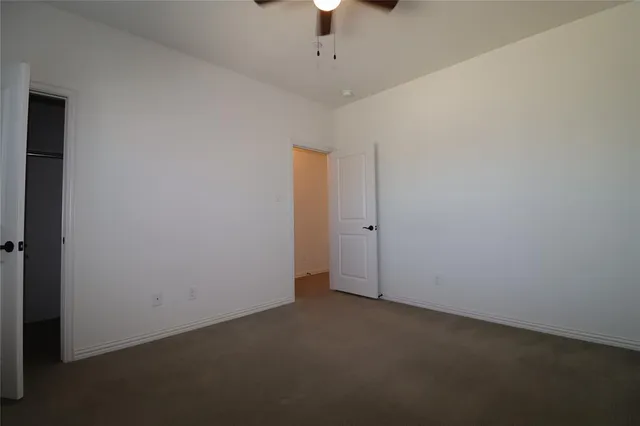 an empty room with a ceiling fan and a window