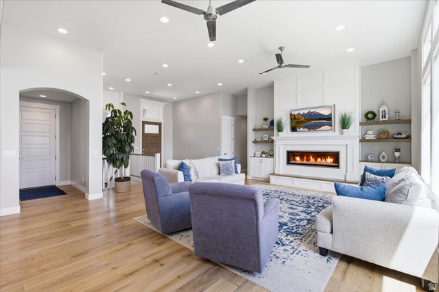 21 Pier Place Tooele, UT 84074 - Photo 9 of 112 Spacious living area featuring a modern linear fireplace, custom built-in shelving, wood-finish flooring, recessed lighting, and ceiling fans