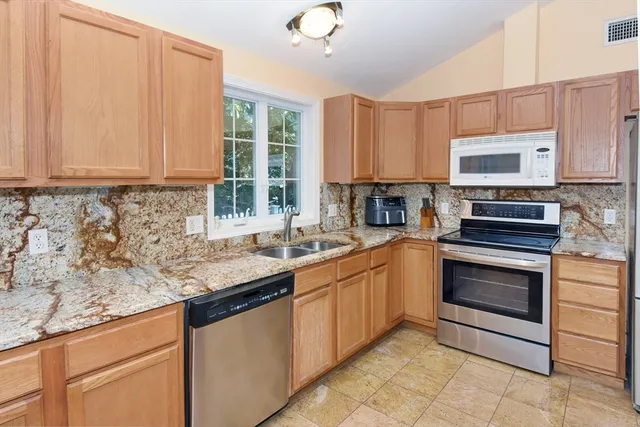 a kitchen with granite countertop a sink stainless steel appliances and cabinets