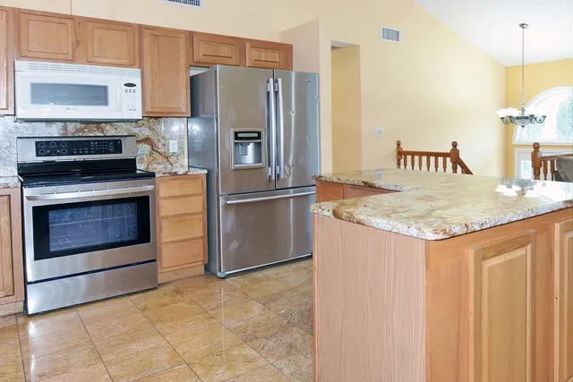 a kitchen with stainless steel appliances granite countertop a refrigerator a stove and a sink