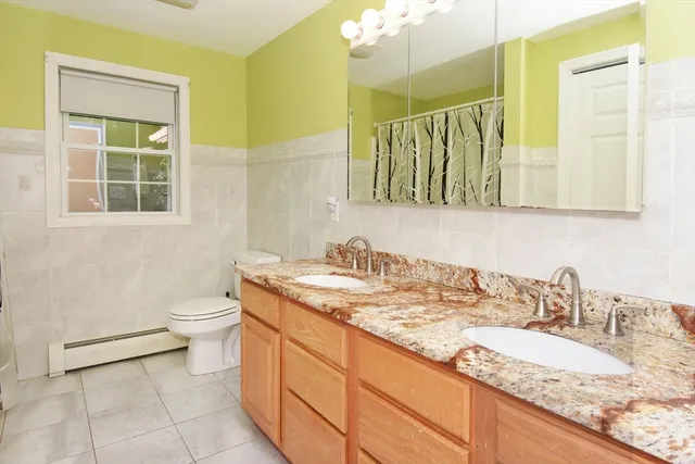a bathroom with a granite countertop sink a toilet and a mirror