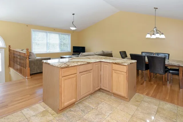 a kitchen with a stove a sink a counter top space and living room view