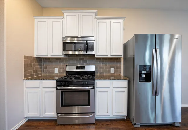 a kitchen with white cabinets and stainless steel appliances