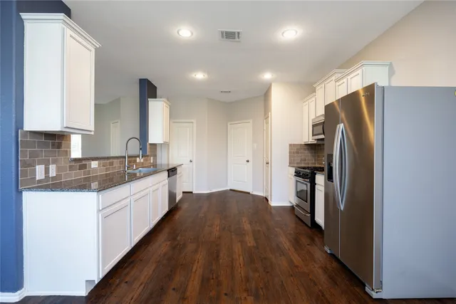 a large kitchen with a lot of counter space and stainless steel appliances