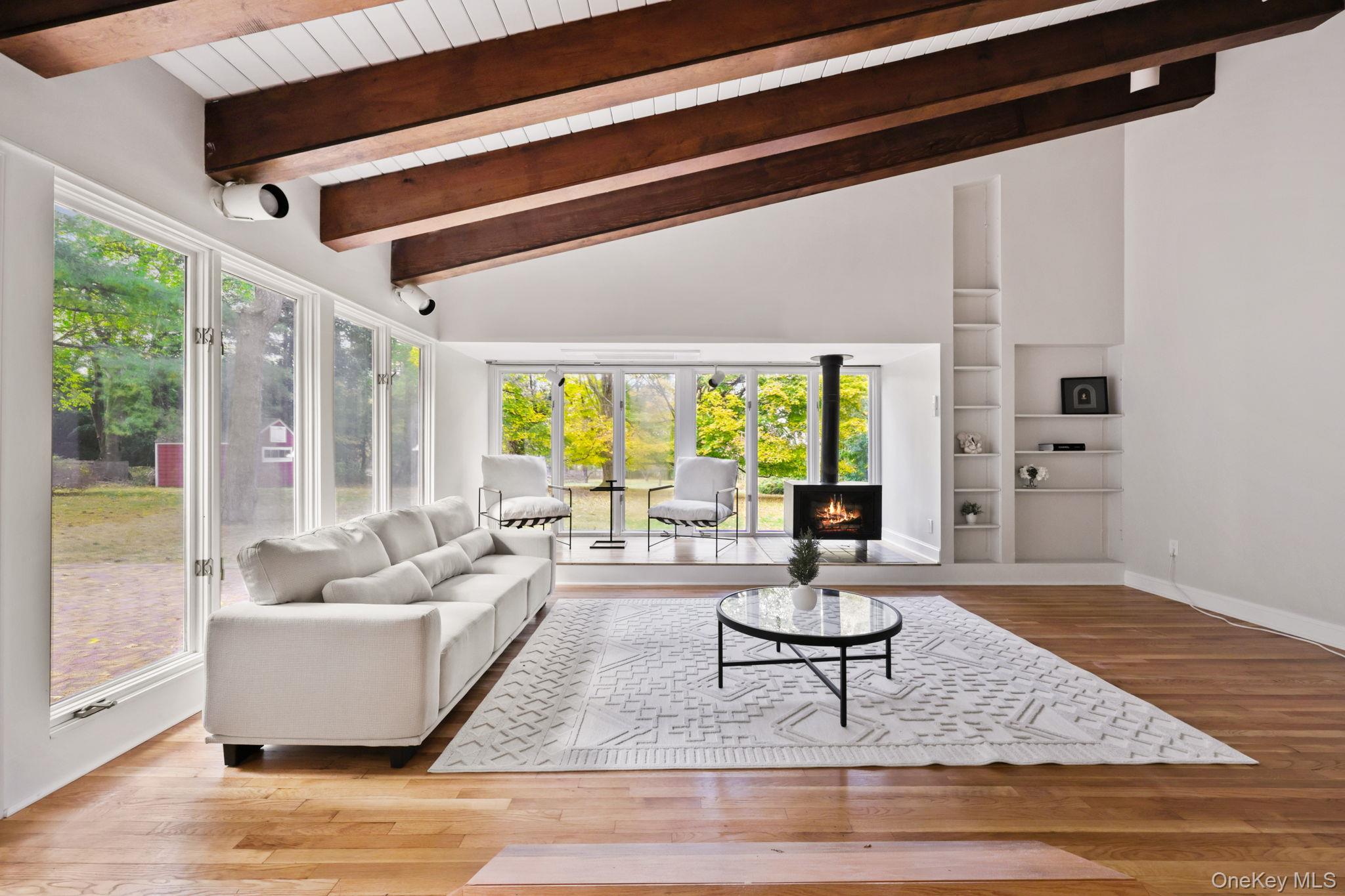 790 Hardscrabble Road Chappaqua, NY 10514 - Photo 20 of 40 Living room featuring light wood finished floors, built in shelves, high vaulted ceiling, a lit fireplace, and a wood ceiling with exposed beams