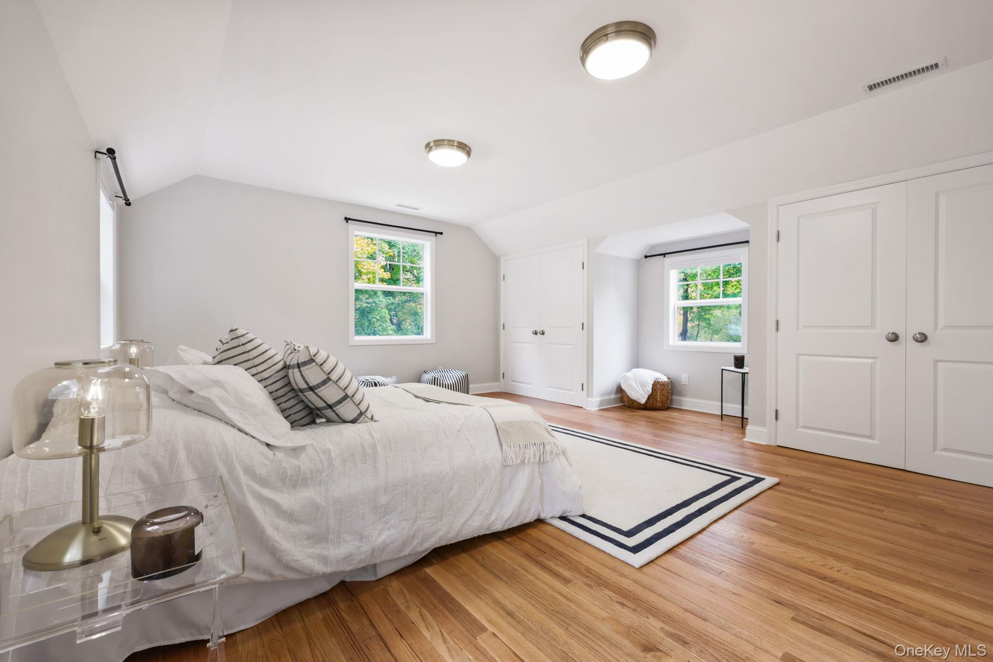 790 Hardscrabble Road Chappaqua, NY 10514 - Photo 34 of 40 Bedroom featuring multiple windows, light wood-style floors, vaulted ceiling, and multiple closets