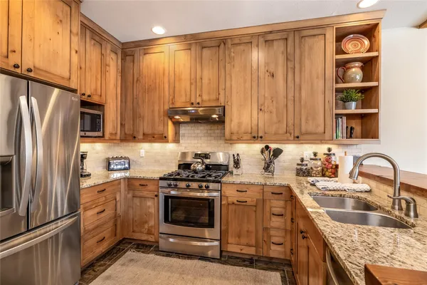 a kitchen with stainless steel appliances granite countertop a sink stove and refrigerator