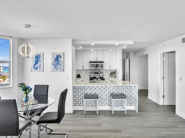 a view of a kitchen with kitchen island stainless steel appliances refrigerator stove a dining table and chair