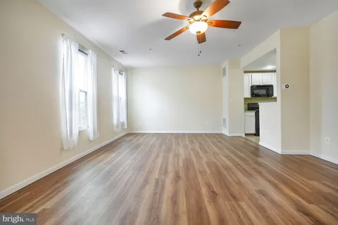 a view of empty room with wooden floor and fan
