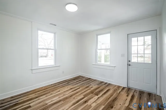 an empty room with wooden floor and windows