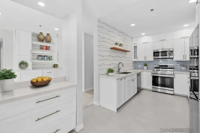 a kitchen with kitchen island a white cabinets and stainless steel appliances