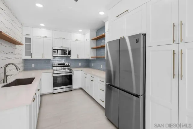 a kitchen with white cabinets stainless steel appliances and sink