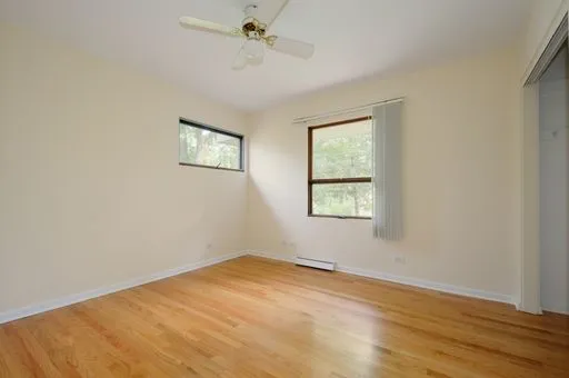 a view of empty room with wooden floor and fan