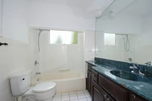 a bathroom with a granite countertop sink a toilet and bathtub