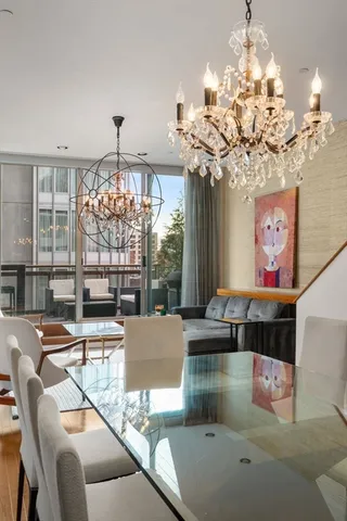a view of a dining room with furniture a chandelier and large windows