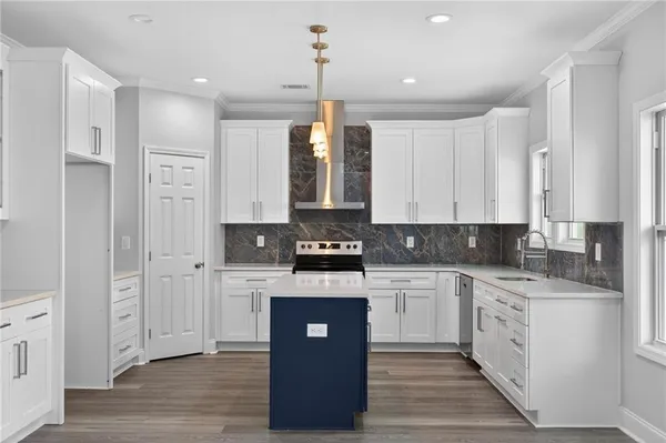 a kitchen with stainless steel appliances granite countertop a stove top oven a sink and white cabinets