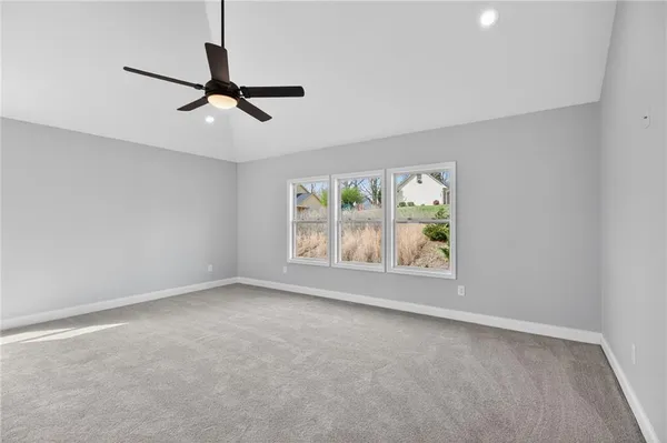 an empty room with windows and ceiling fan