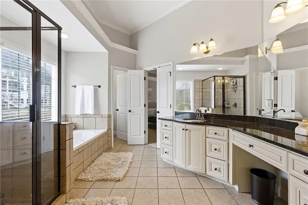 a large bathroom with a granite countertop double vanity sink a mirror and a bathtub