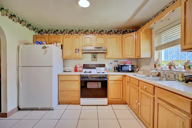 a kitchen with granite countertop a refrigerator sink stove and cabinets