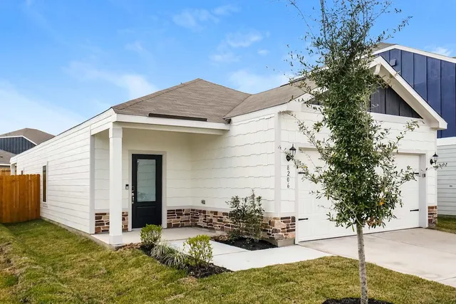a view of an empty room and a kitchen with wooden floor