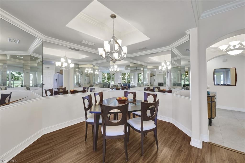 1276 Rialto Way, Unit 101 Naples, FL 34114 - Photo 13 of 37 a view of a dining room with furniture a chandelier and wooden floor