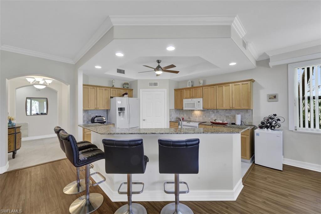1276 Rialto Way, Unit 101 Naples, FL 34114 - Photo 10 of 37 a kitchen with stainless steel appliances granite countertop a stove top oven a sink dishwasher a dining table and chairs with wooden floor