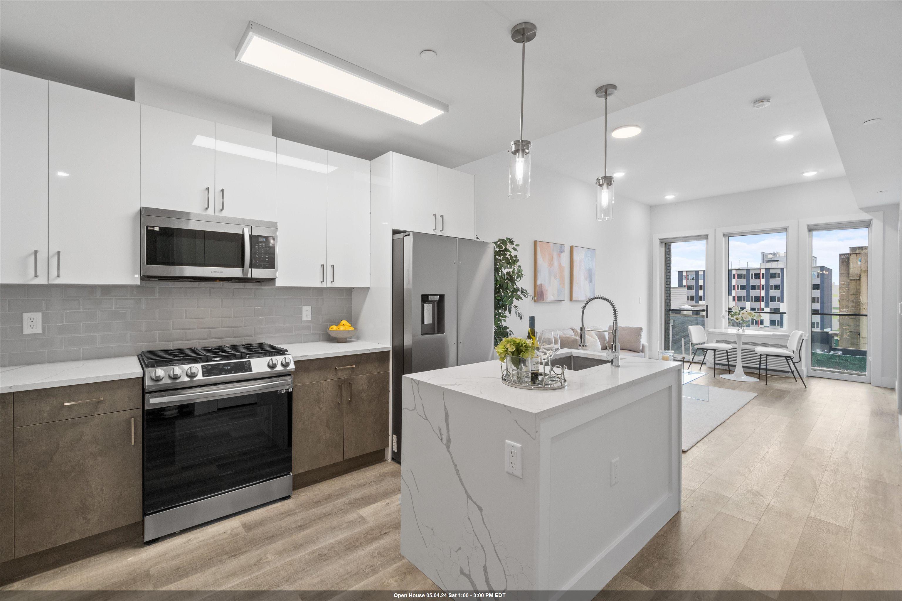 a kitchen with stainless steel appliances kitchen island granite countertop a stove a refrigerator a sink a stove and white cabinets with wooden floor
