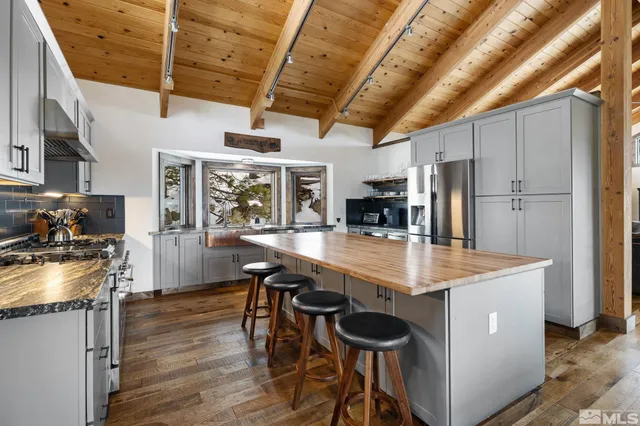 a kitchen with stainless steel appliances granite countertop a table chairs and a refrigerator