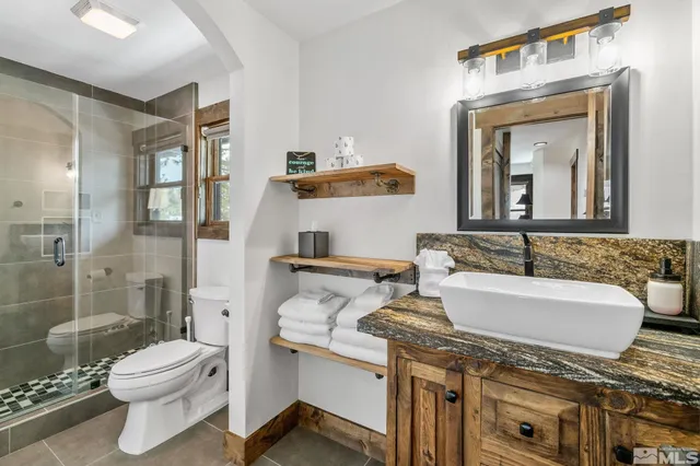 a bathroom with a granite countertop sink mirror vanity and toilet