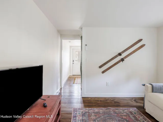 a view of a hallway with wooden floor and a flat screen tv