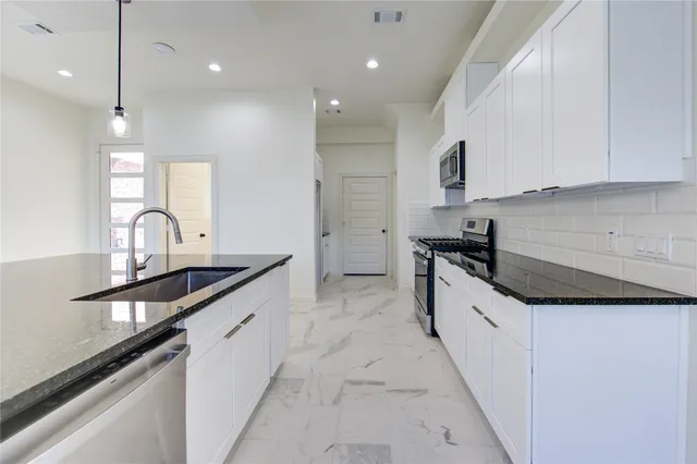 a kitchen with stainless steel appliances granite countertop a sink stove and cabinets