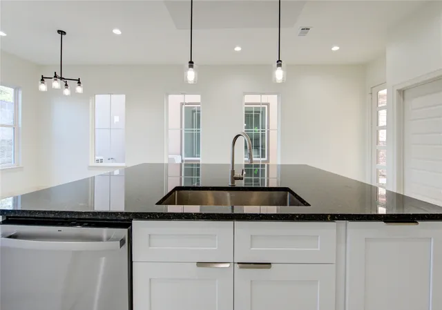 a kitchen with kitchen island granite countertop a sink a counter space and cabinets