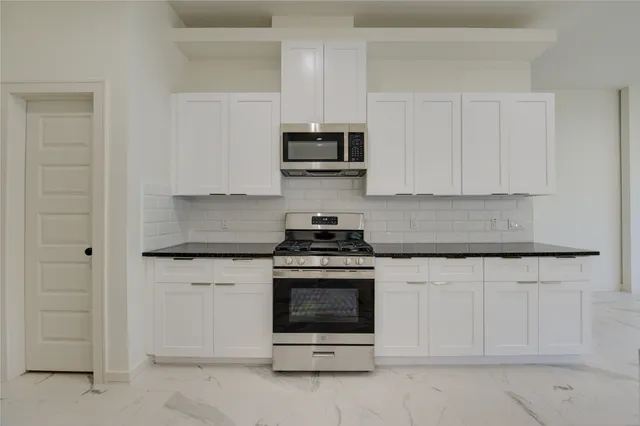 a kitchen with stainless steel appliances granite countertop a stove and a microwave