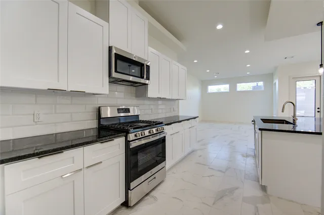 a kitchen with stainless steel appliances granite countertop a sink a stove and a microwave