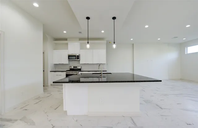 a kitchen with stainless steel appliances granite countertop a sink and a refrigerator