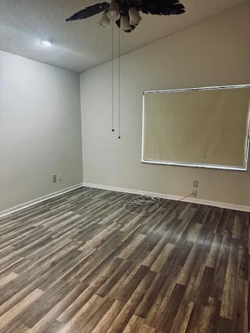 an empty room with wooden floor closet and windows