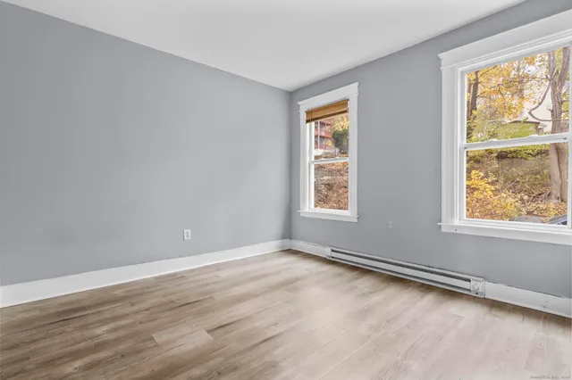 an empty room with wooden floor and windows