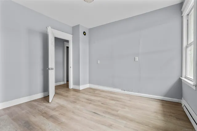 a view of an empty room with wooden floor and a window