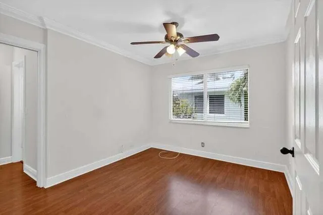 a view of an empty room with wooden floor and a window