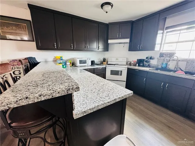 a kitchen with granite countertop wood cabinets a stove top oven a sink and dishwasher