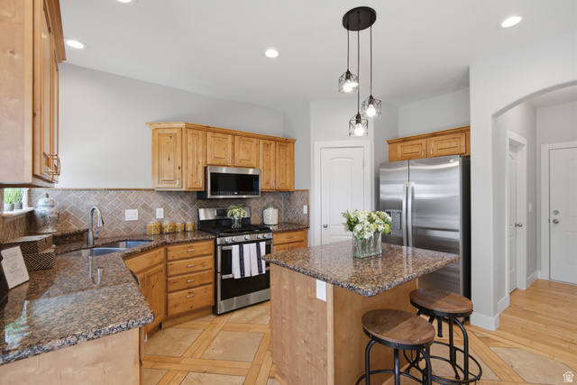 1252 Skyline Road Saratoga Springs, UT 84045 - Photo 14 of 51 Kitchen featuring a central island with countertop seating, stainless steel appliances, wood cabinetry, recessed lighting, and a tile backsplash