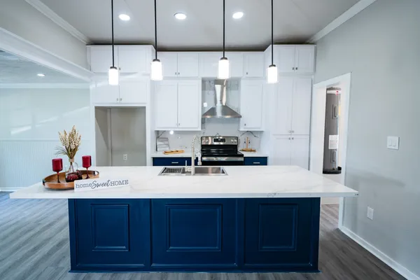a kitchen with stainless steel appliances granite countertop a sink dishwasher stove and white cabinets with wooden floor
