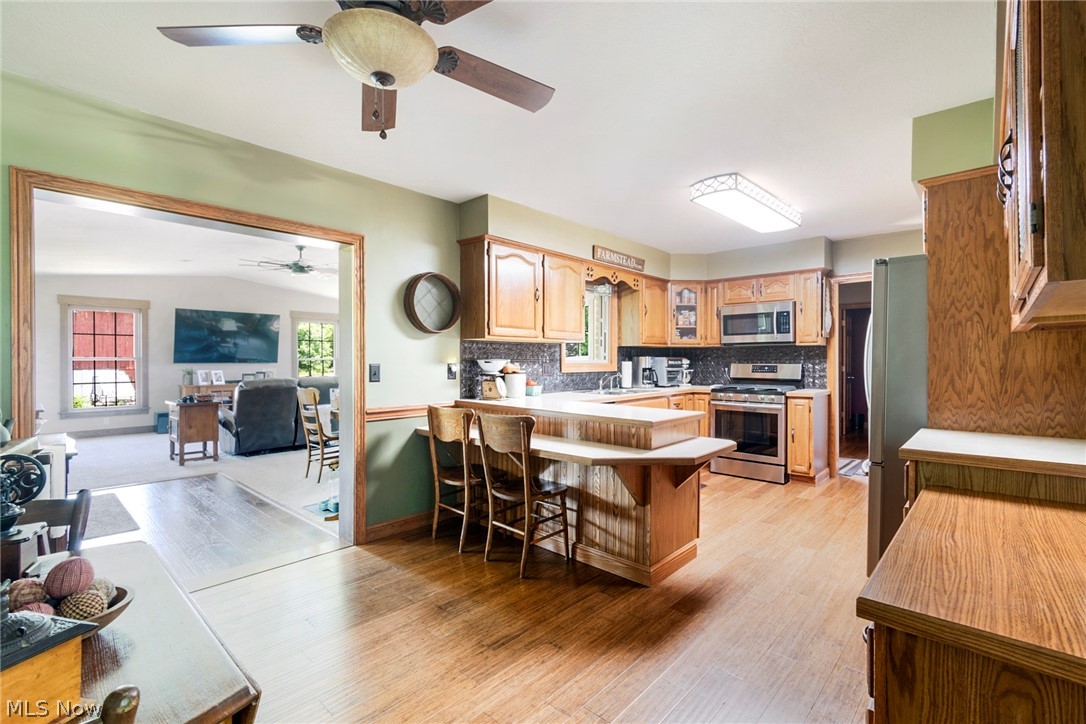 11711 Bandy Road Alliance, OH 44601 - Photo 28 of 50 Kitchen with kitchen peninsula, ceiling fan, stainless steel appliances, and backsplash