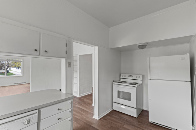 180 South 300 East Logan, UT 84321 - Photo 10 of 35 Kitchen featuring white appliances, white cabinetry, vinyl floors, light countertops, and crown molding