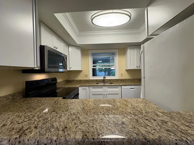 a room with kitchen island a sink stainless steel appliances and cabinets