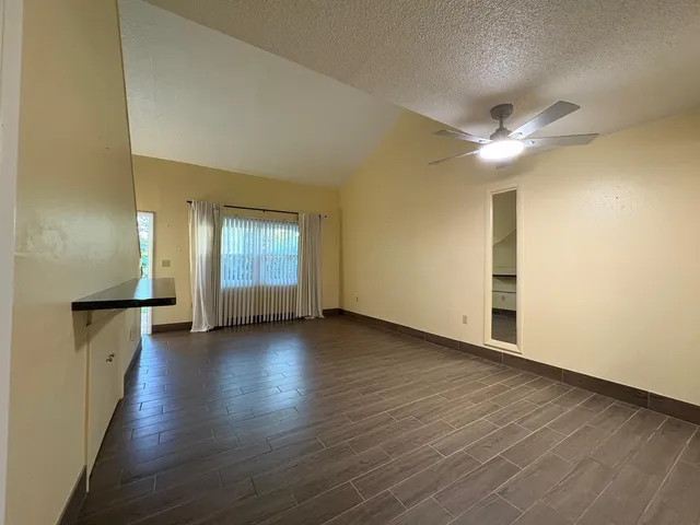 an empty room with wooden floor and ceiling fan